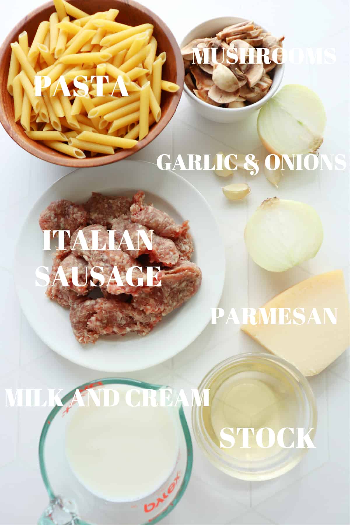 Ingredients for creamy sausage pasta dish on a white tile board.