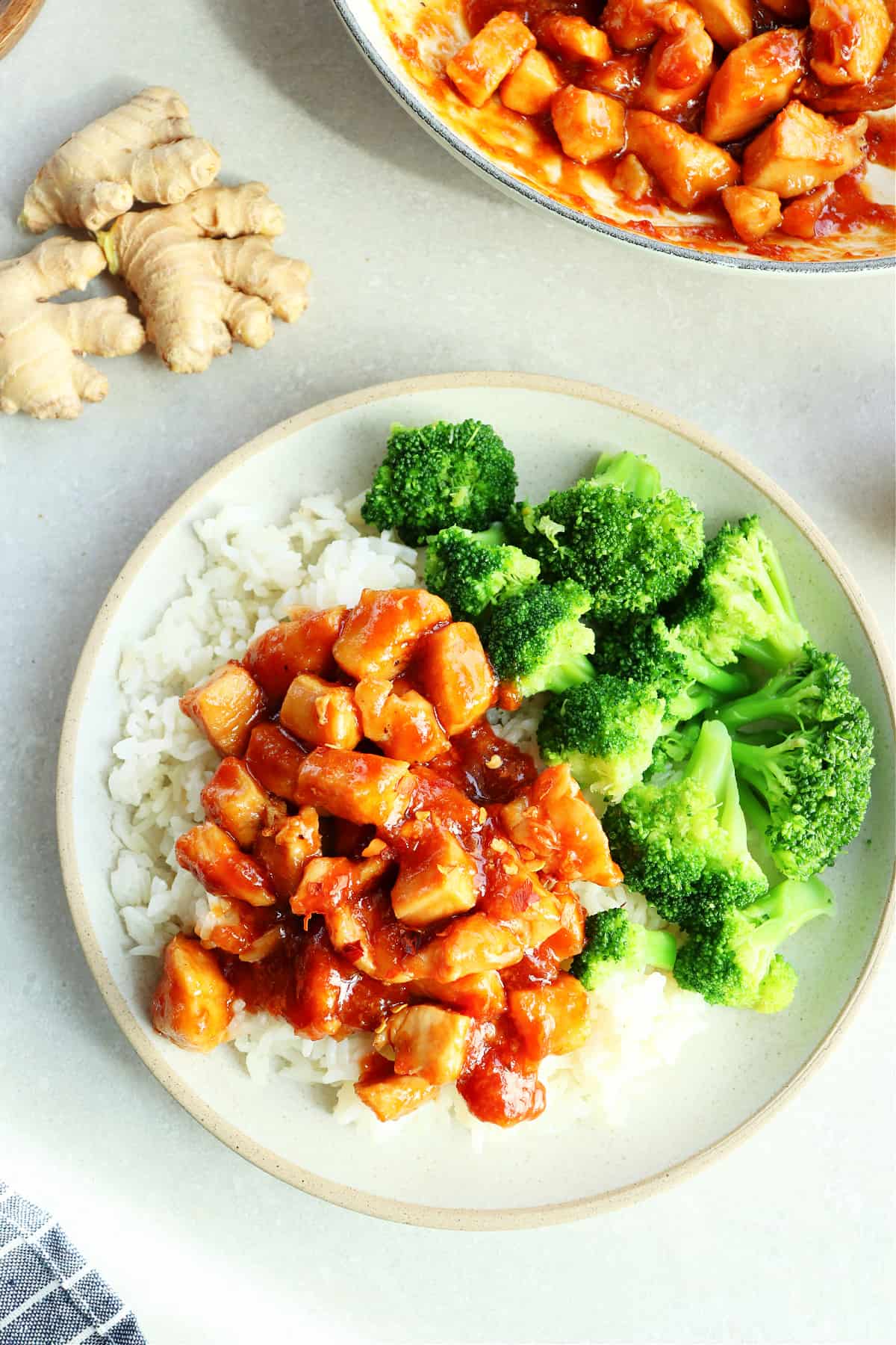 Overhead photo of rice with chicken in ginger soy sauce and broccoli on a gray plate.