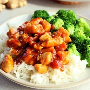 Ginger soy chicken on rice with broccoli on a plate.