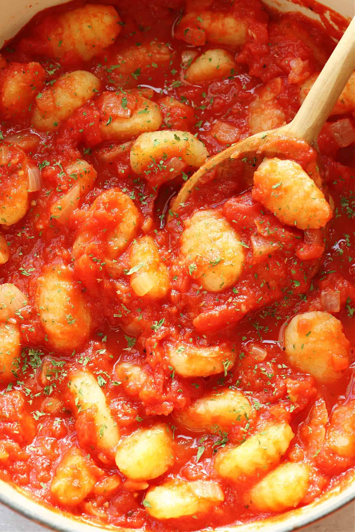 Gnocchi and tomato sauce in a pot with wooden spoon.