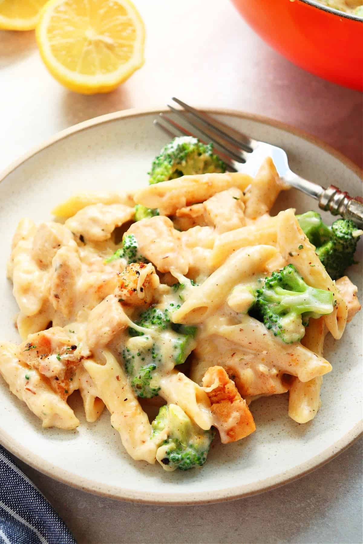 Penne pasta with chicken and broccoli in creamy sauce on a plate with fork.