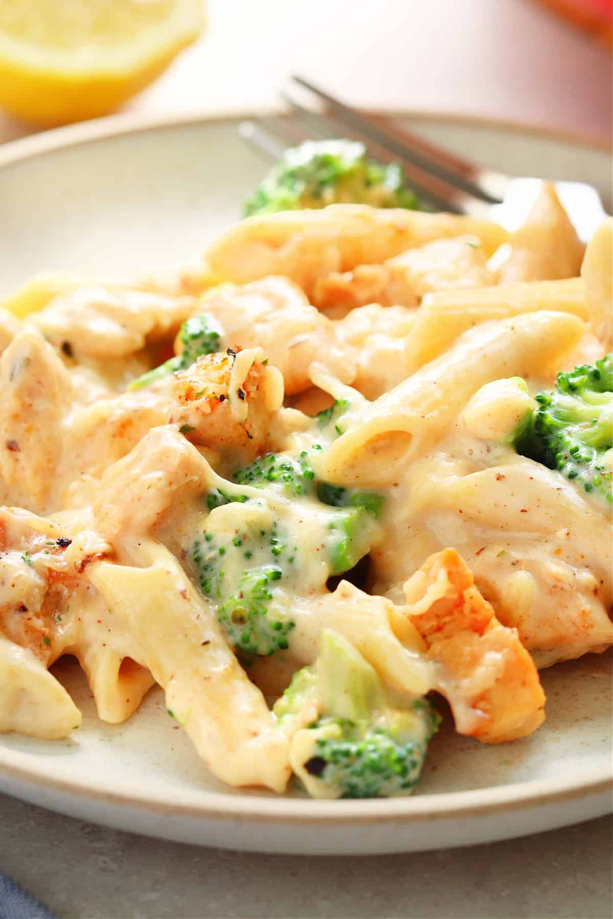 Chicken and broccoli pasta on a plate with fork.