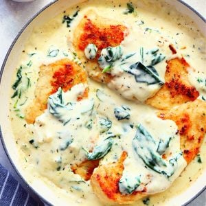 Square image of chicken Florentine dish in a white skillet.