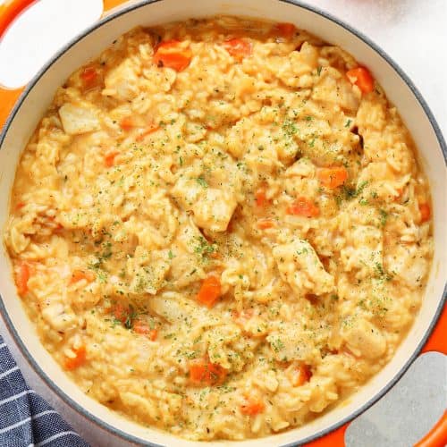 Square image of chicken and rice in an orange pot.