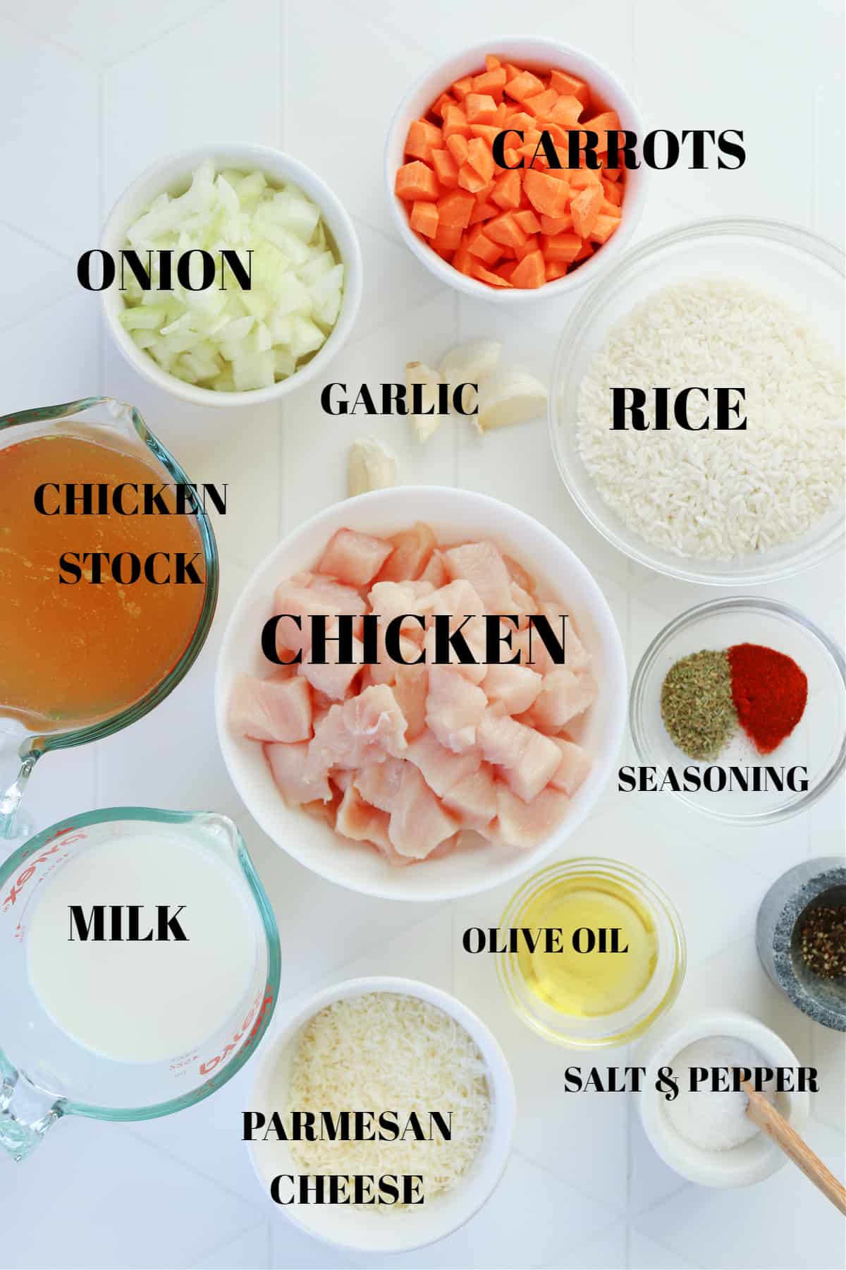All ingredients for chicken and rice dish in bowls on a white tile board.