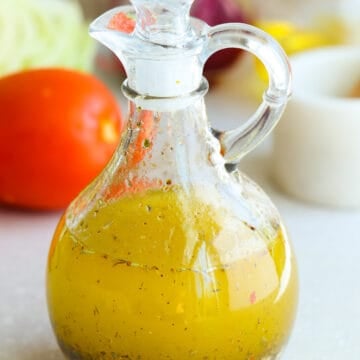 Italian salad dressing in a glass cruet on a gray board.