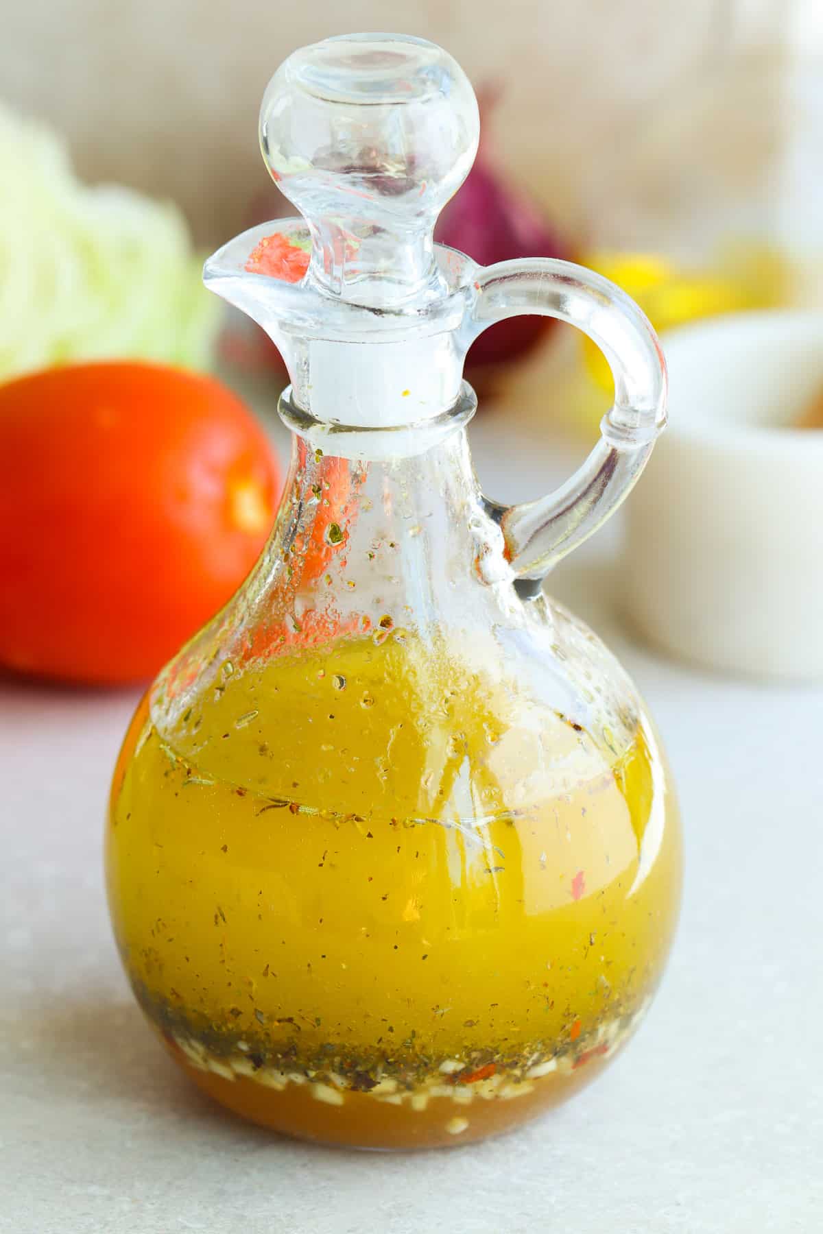 Italian salad dressing in a glass cruet on a gray board.