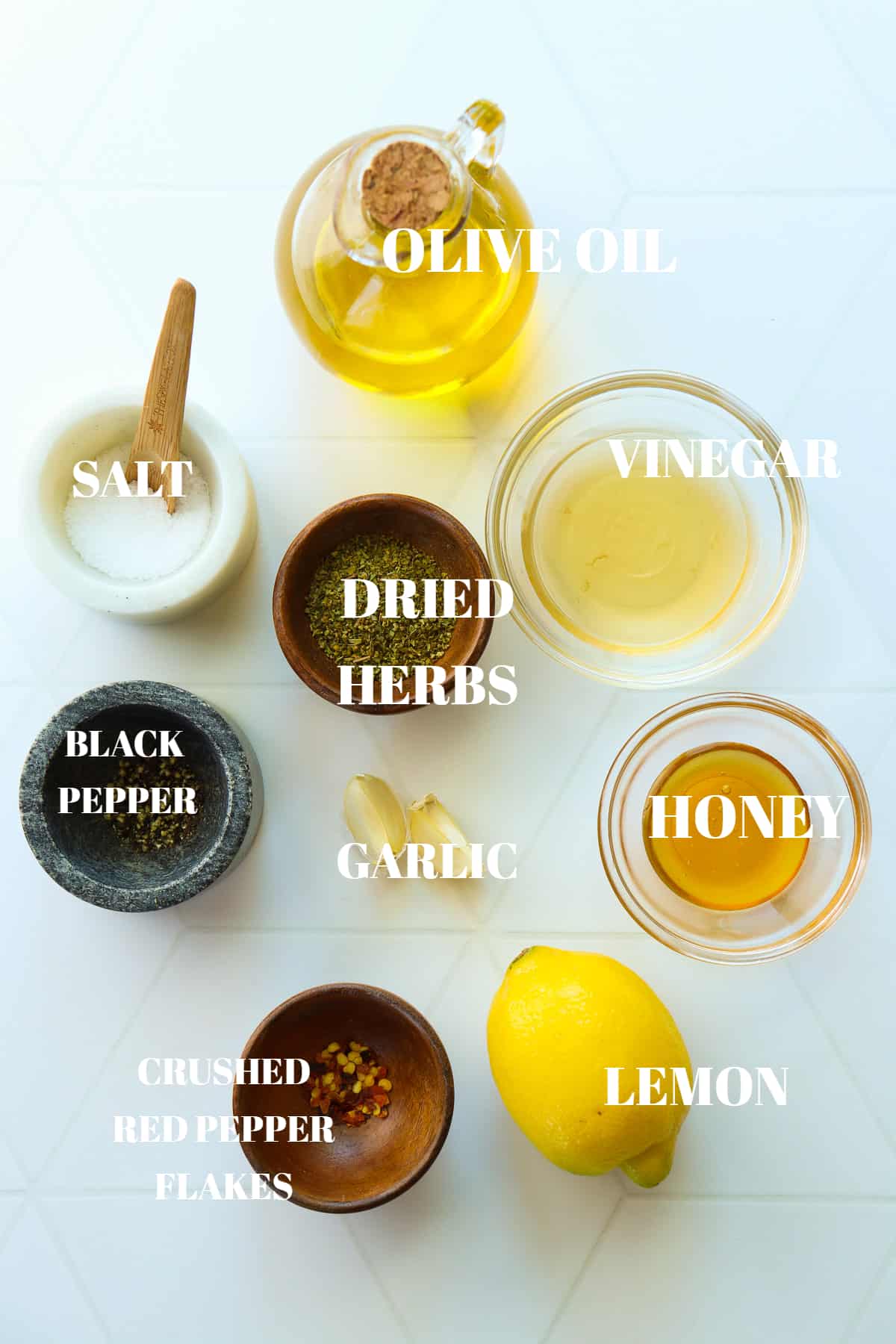 All ingredients for Italian dressing in bowls on a white tile board.