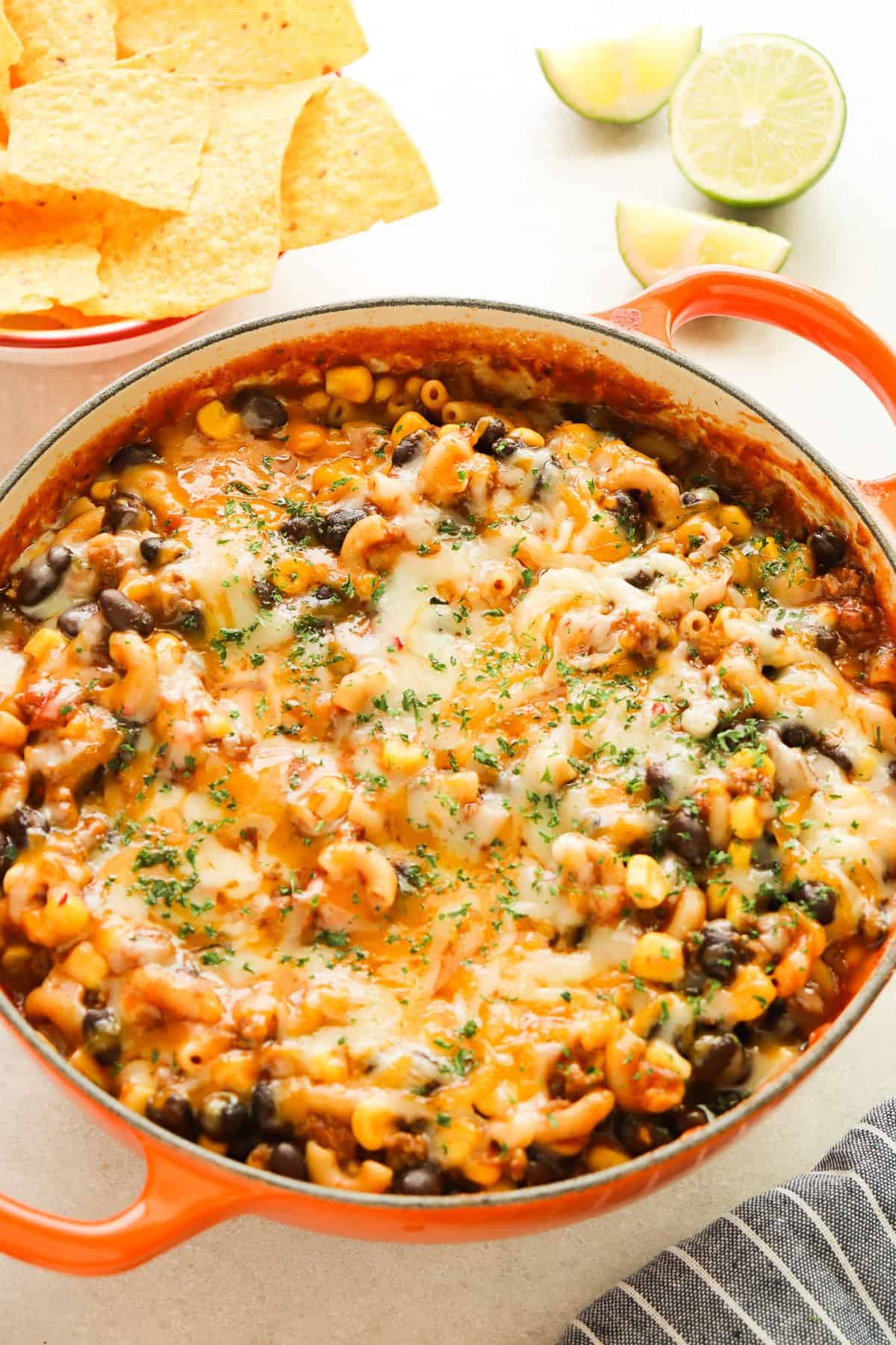 Macaroni with taco meat and melted cheese on top in an orange Le Creuset pan.