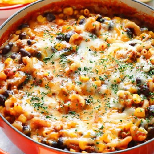Pasta with taco beef, corn and beans with cheese topping in a deep pot.