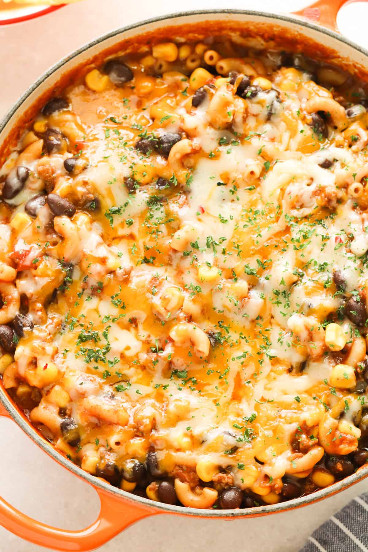 Macaroni pasta dish with black beans and melted cheese in a Dutch oven.