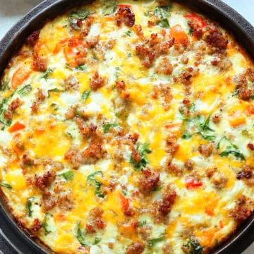 Quiche with potato crust and vegetable and sausage filling, baked in a cast iron casserole dish.