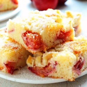 Square image of three slices of plum coffee cake on a dessert plate.